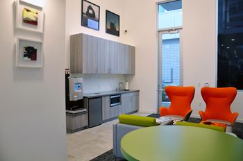 A modern kitchen with a green table and orange chairs.